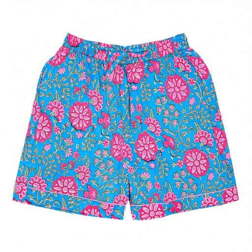 A pair of pyjama shorts with a vibrant turquoise blue background and a pink-and-green block-print floral design, laid flat against a white background.