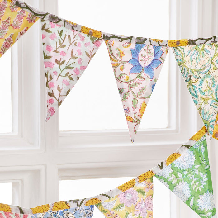 Colorful floral fabric bunting hanging against a white window frame.