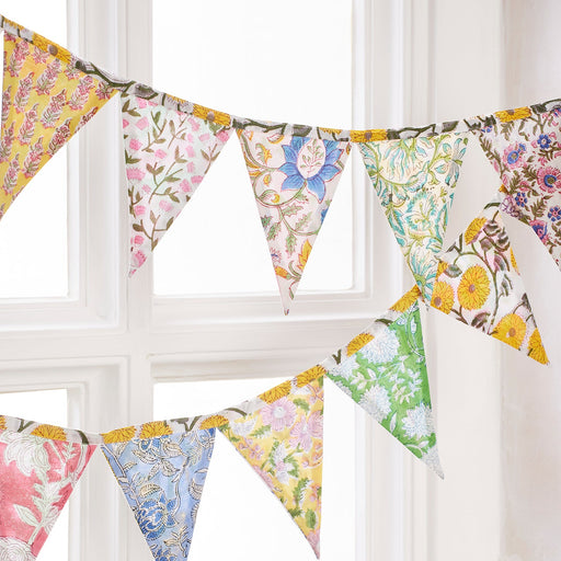 Floral patterned bunting hanging against a white window frame.