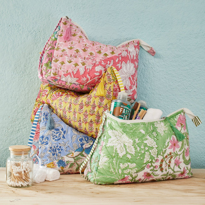 Colourful block-printed fabric wash bags on a wooden surface with a light blue wall background