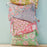 Stack of colourful block-printed fabric bags with floral patterns  set against a light blue wall