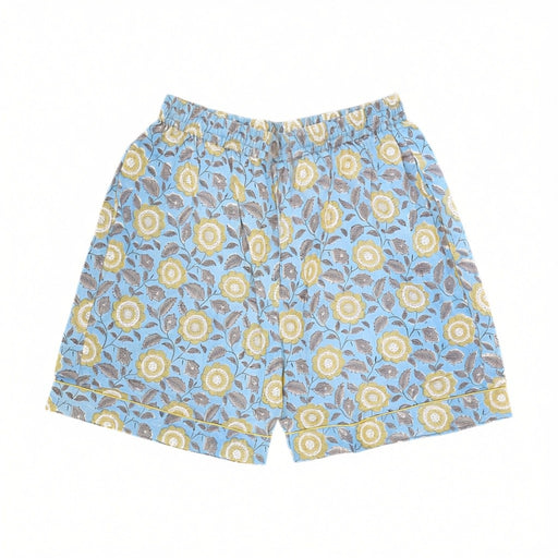 Light blue pyjama shorts with an all-over floral block print pattern in yellow, brown, and white, featuring an elastic waistband.  Set against a white background.