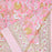 Pink cotton tablecloth with golden and white floral patterns folded at one corner