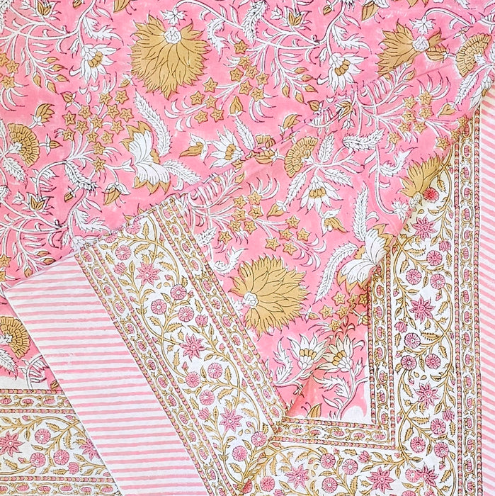 Pink cotton tablecloth with golden and white floral patterns folded at one corner