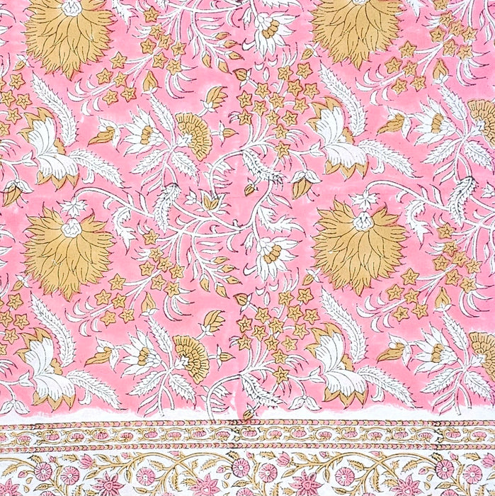Floral patterned fabric with gold and white flowers on a pink background