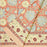 Folded terracotta rust and slate blue hand-block printed botanical themed cotton tablecloth with ticking-stripe edge.