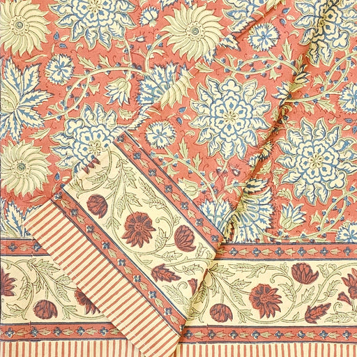 Folded terracotta rust and slate blue hand-block printed botanical themed cotton tablecloth with ticking-stripe edge.