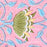 A close-up of a pink patterned surface featuring a stylized green leaf or lotus shape with yellow and white accents, surrounded by light blue leaf motifs and curved blue lines.