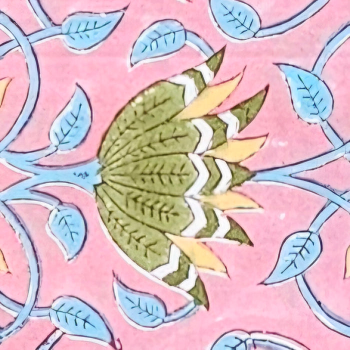 A close-up of a pink patterned surface featuring a stylized green leaf or lotus shape with yellow and white accents, surrounded by light blue leaf motifs and curved blue lines.