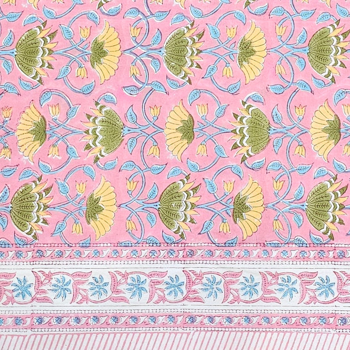 Pink tablecloth with a traditional hand-block print pattern featuring yellow flowers, green and yellow lotus motifs, and light blue vines, finished with a decorative border.