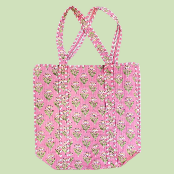 Pink tote bag with green floral pattern on a light green background
