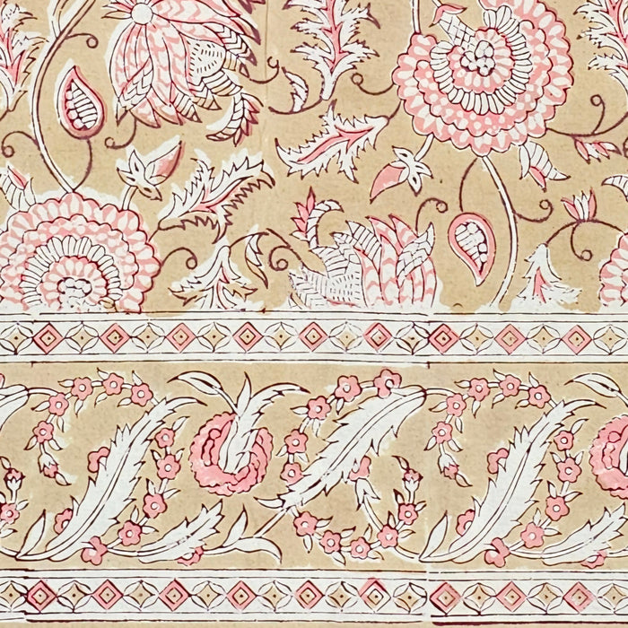 Decorative floral block printed tablecloth with pink and white elements on a beige background