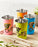 Set of colourful stainless steel tumblers with bicycle designs on a wooden tray.