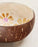 Coconut shell bowl with floral design on a light background