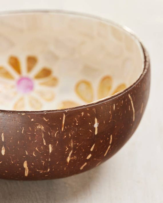 Coconut shell bowl with floral design on a light background