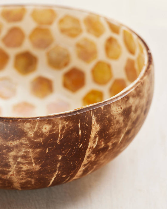Coconut shell bowl with honeycomb pattern on a light background