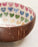 Coconut shell bowl with colorful heart pattern inside on a light background