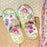 Colorful floral-patterned slippers on a wooden surface with a textured white background.