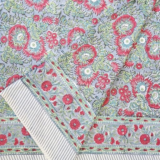 Handcrafted 100% cotton tablecloth in Slate Garden print, showing crimson red flowers, sage green leaves on a blue-grey background, and matching striped hem detail.  Folded back.