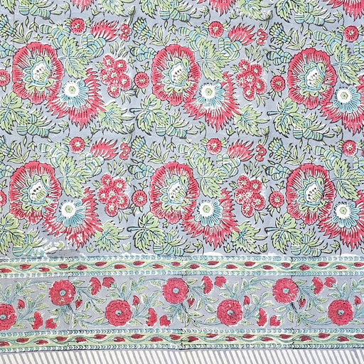 Handcrafted 100% cotton tablecloth in Slate Garden print, showing crimson red flowers, sage green leaves on a blue-grey background, and matching striped hem detail.