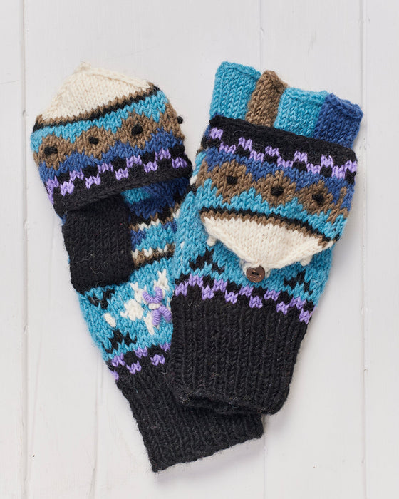 A pair of hand knitted Snowflake Hunter Gloves on a whitewashed wooden background.