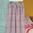 Floral-patterned pajama pants hanging on a rack against a colorful background.