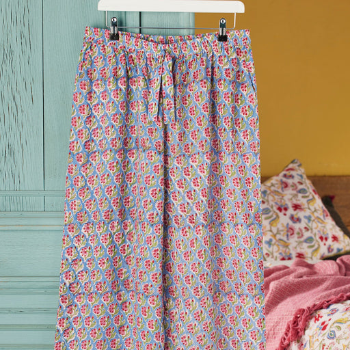 Floral-patterned pajama pants hanging on a rack against a colorful background.