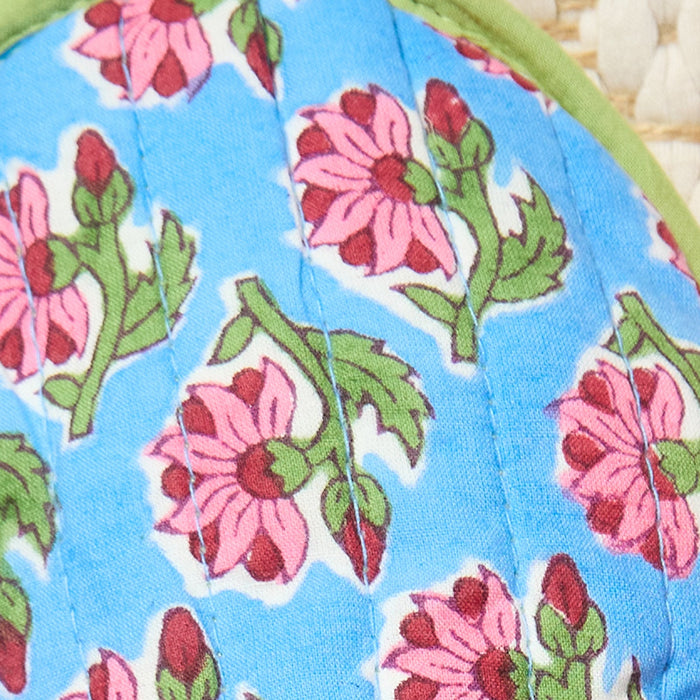 Floral patterned fabric with pink flowers and green leaves on a blue background