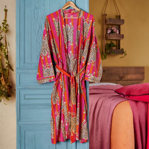 Colourful patterned robe with a tiger print hanging on a blue door with a bed in the background