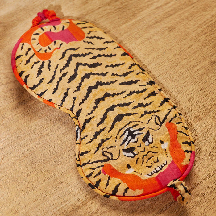 Sleep mask with tiger design on a wooden surface