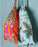 Drawstring bags with tiger print hanging on a wooden surface.