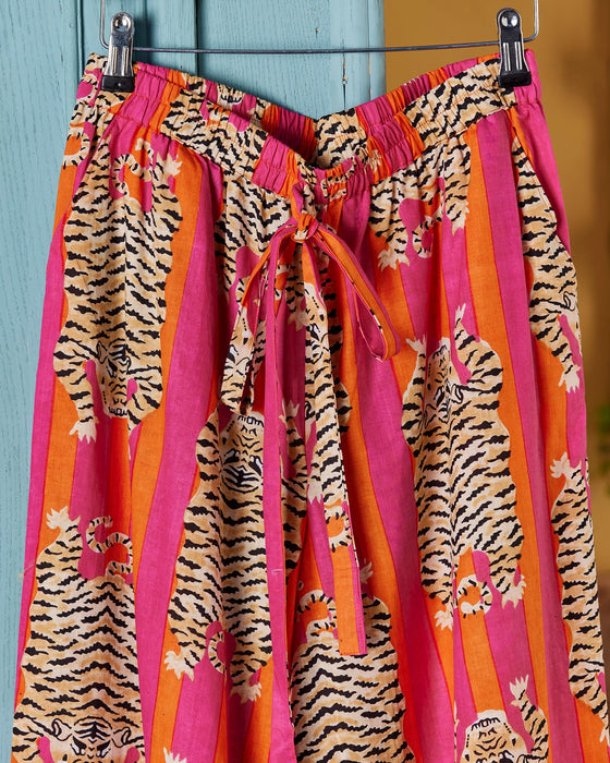 Colourful pyjama bottoms with a tiger pattern on a hanger against a blue wall.