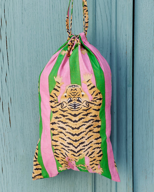 Drawstring bag with tiger design and pink and green stripes on a wooden surface