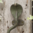 Close up pictaure of a Decorative brass cobra handle with a green patina on a white washed wooden door with ivy leaves.