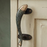 Decorative fish-shaped brass door handle with a green patina on a wooden door
