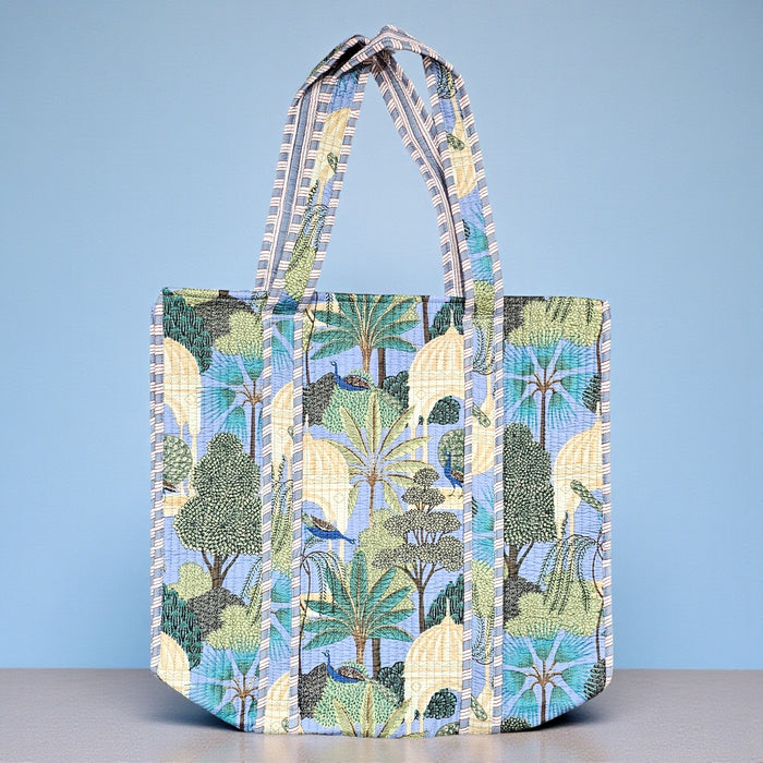 Quilted cotton tote bag featuring a tropical pattern of peacocks and domed temples on a soft light blue background.