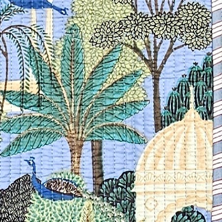 Close-up of the Peacock Temple quilted cotton tote bag, showing a tropical textile scene with palm trees, a peacock, and a domed temple on a soft blue background.