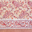 A close-up of a printed cotton tablecloth featuring red and orange paisley and floral motifs on a warm peach background, with a decorative border running horizontally across the lower portion.