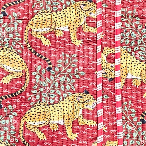Textile with yellow leopards and green leaves on a red background