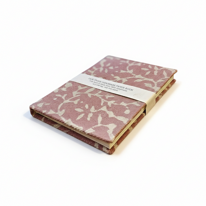 Pink notebook with white floral pattern on a light green background