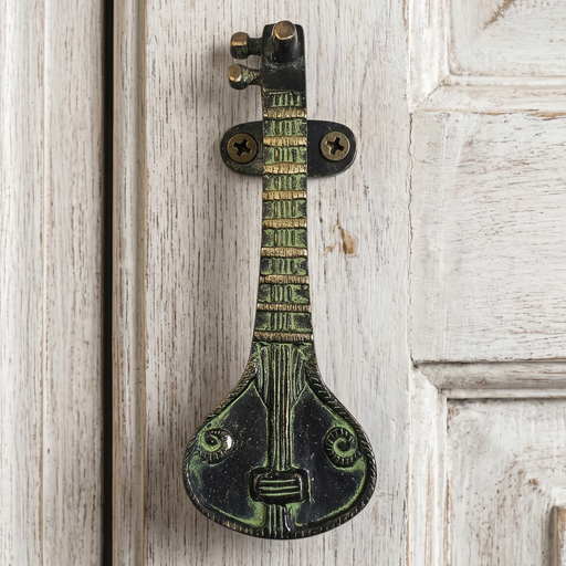 Decorative Sitar brass door handle with a green patina on a whitewashed wooden door
