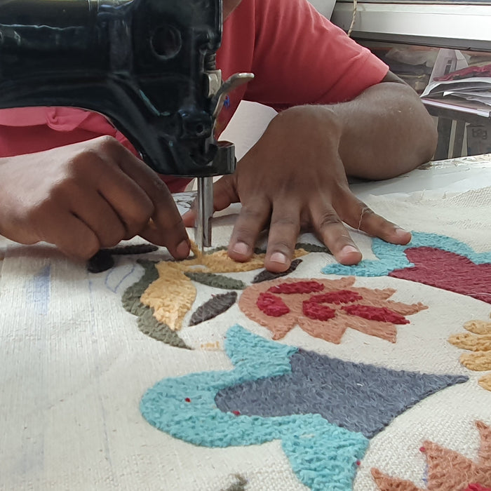 Phtograph showing an artisan hand embroidering a cushion cover